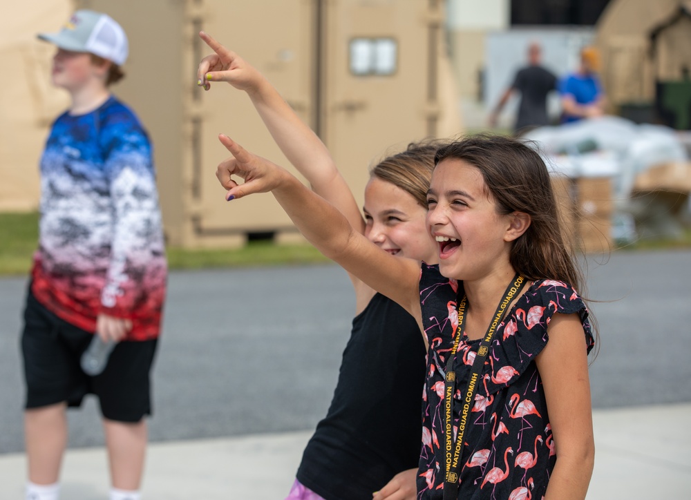 Two children pointing at the sky in excitement during the Thunder Over New Hampshire airshow family day at Pease Air National Guard Base